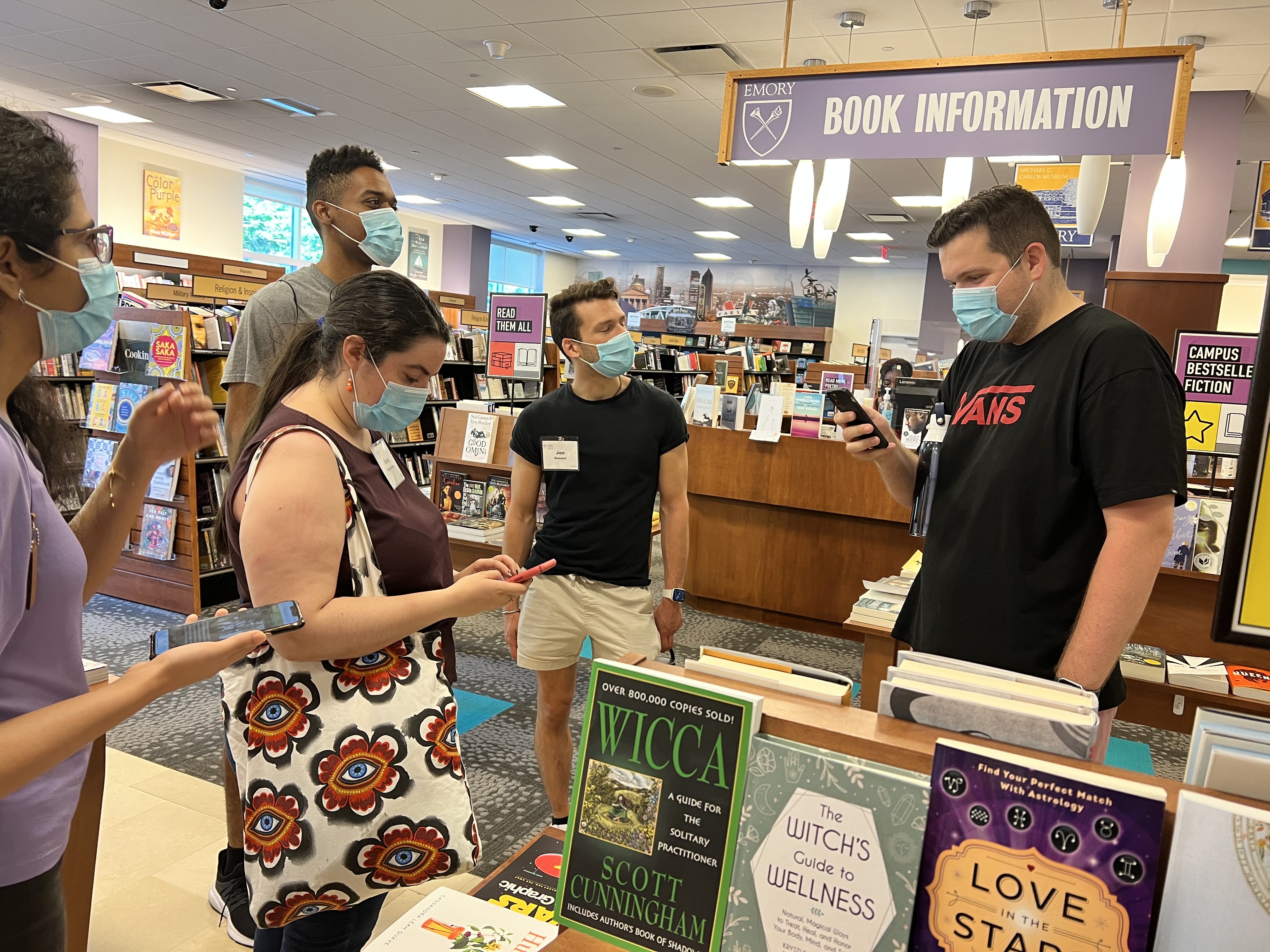 5 adults standing in a book store most holding phones