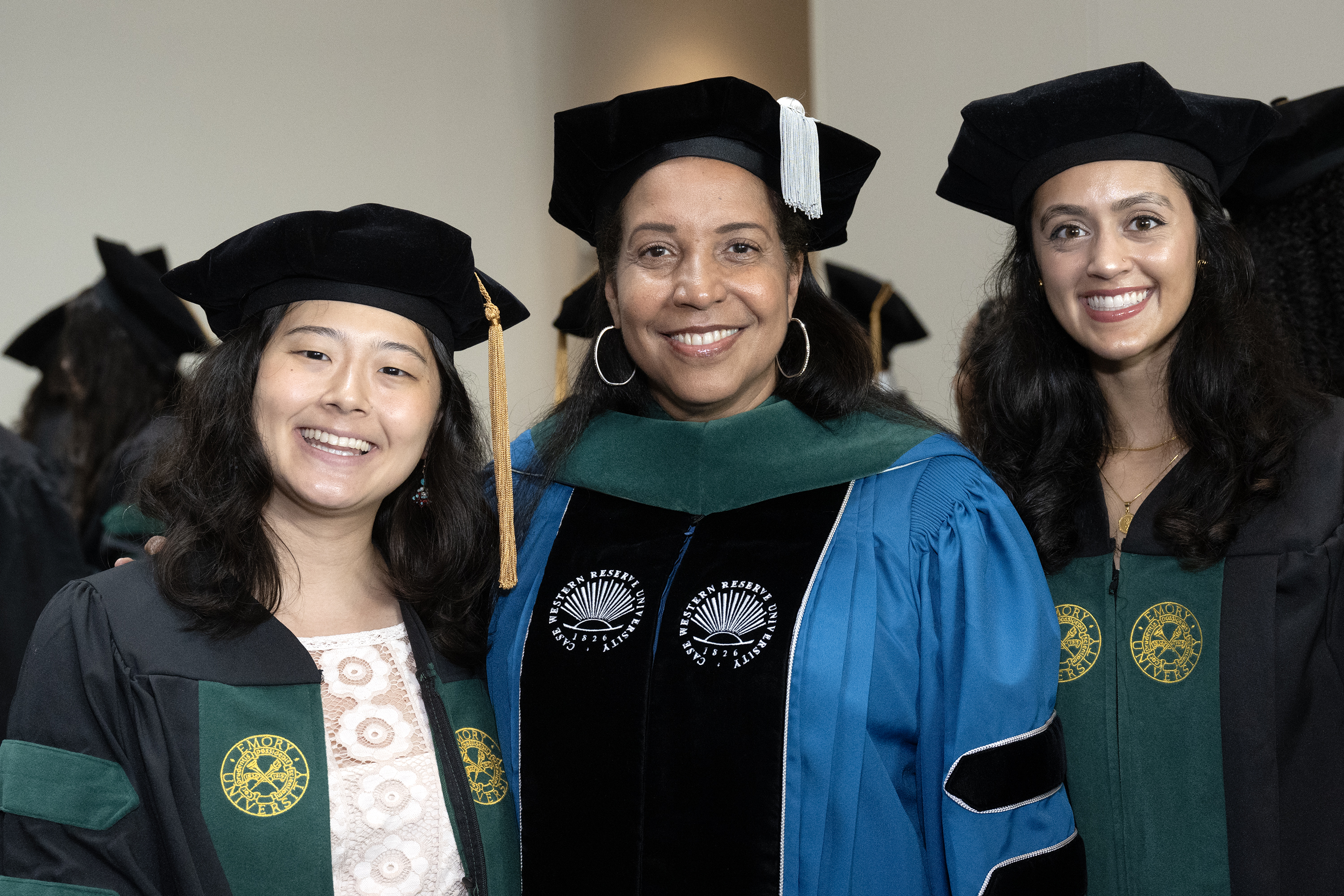 2 graduates smiling with faculty member