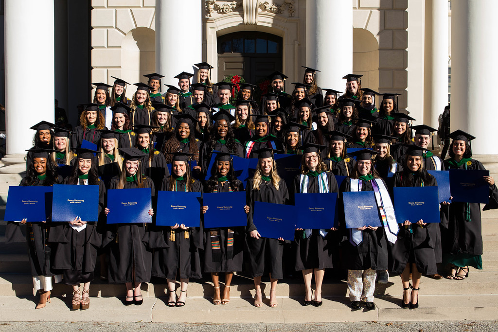 large group of graduates smiling and folder large blue folders
