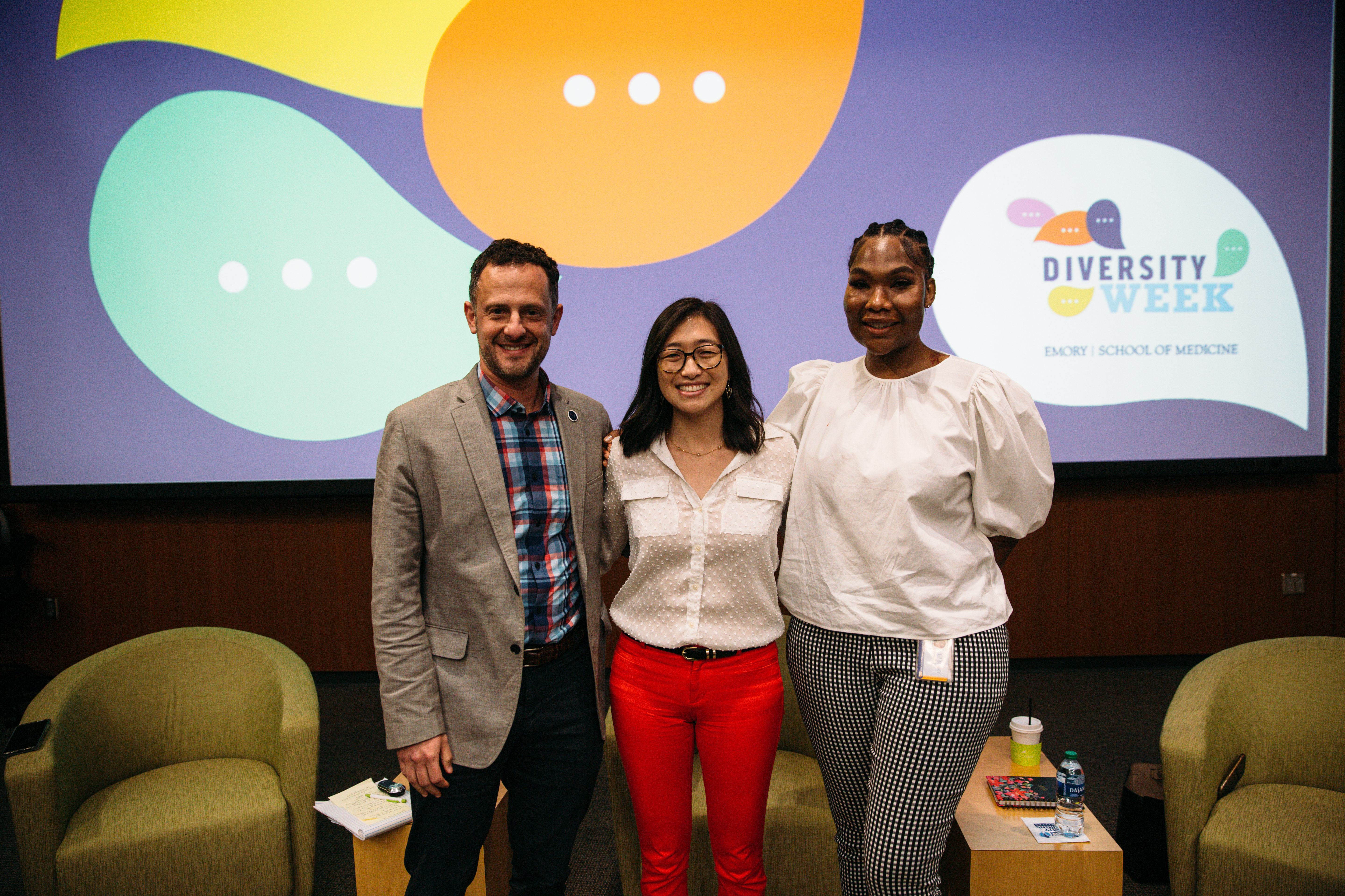 Three people stand in front of a screen with the Diversity and Inclusion Week logo