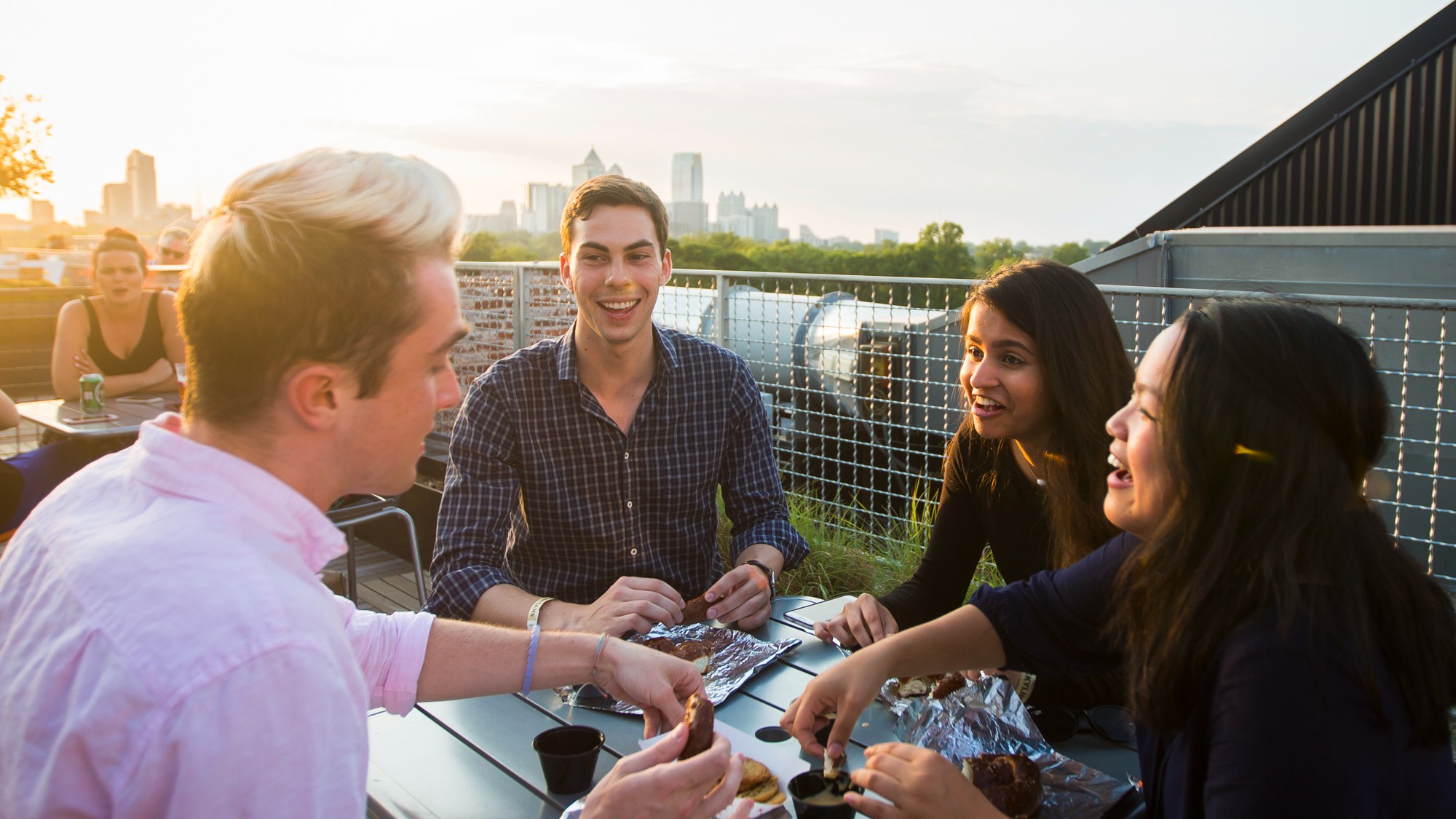 Group of people on a rooftop eating and talking