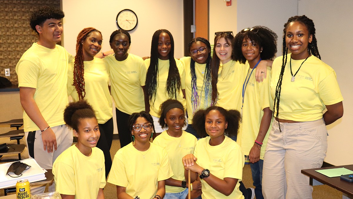 Group of high school students posing in a classroom wearing matching yellow shirts