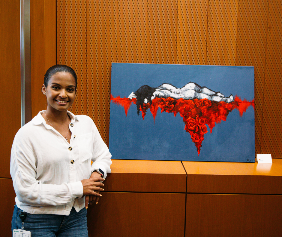 Student stands in front of her art work painted on canvas