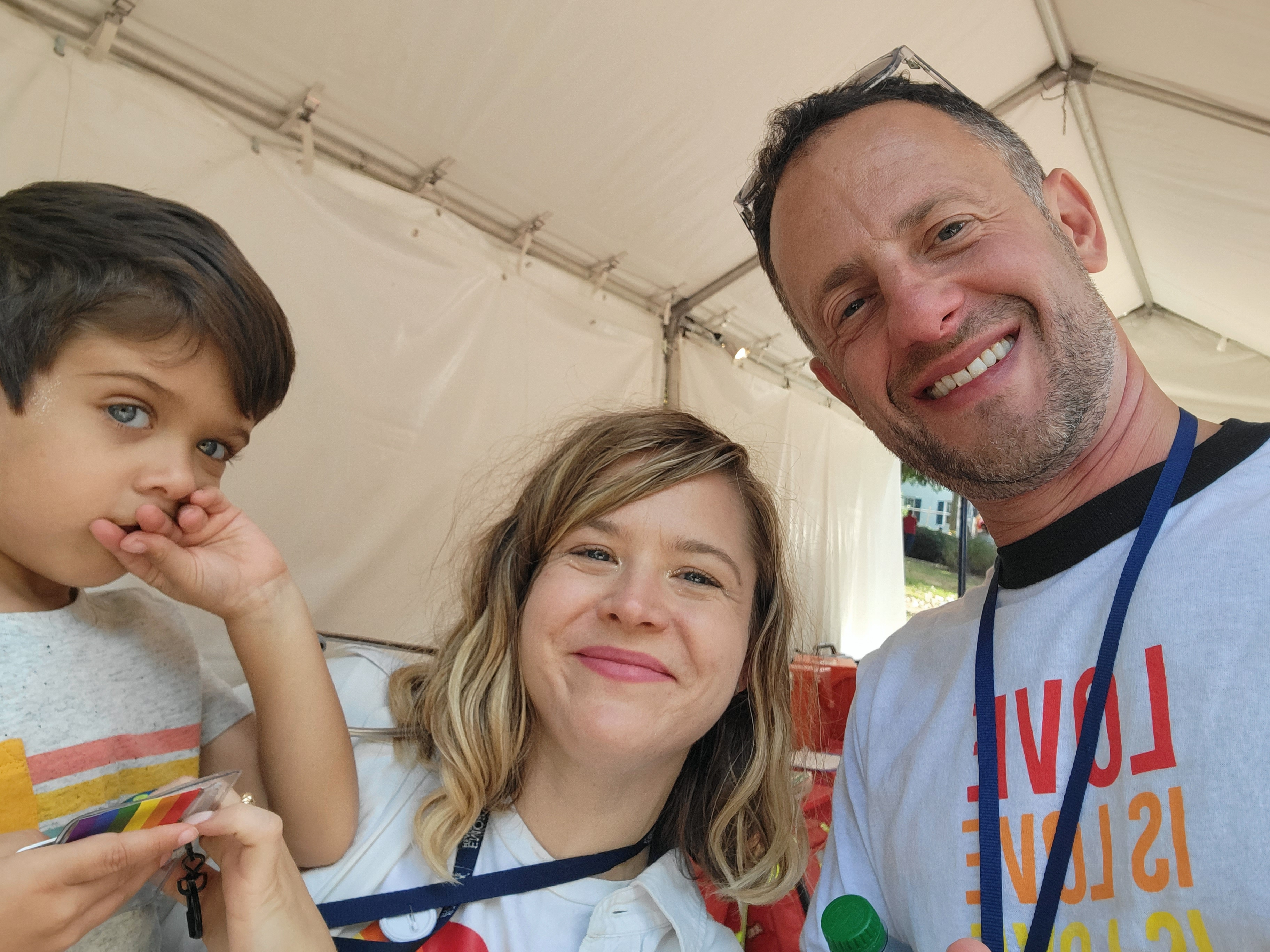 Man, woman and child smile for a photo at a Pride event