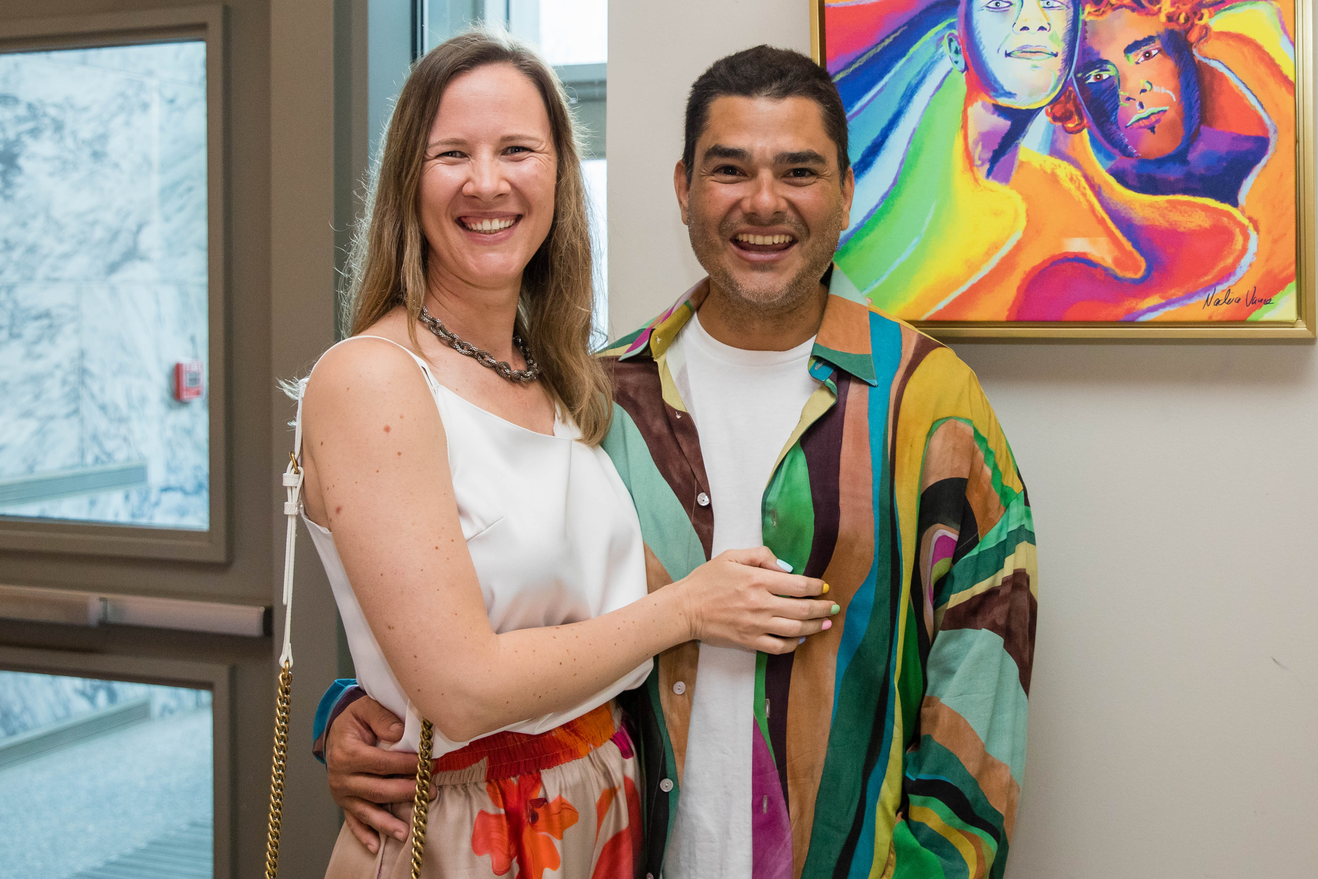 A man and a woman stand in front of art work together for a photo