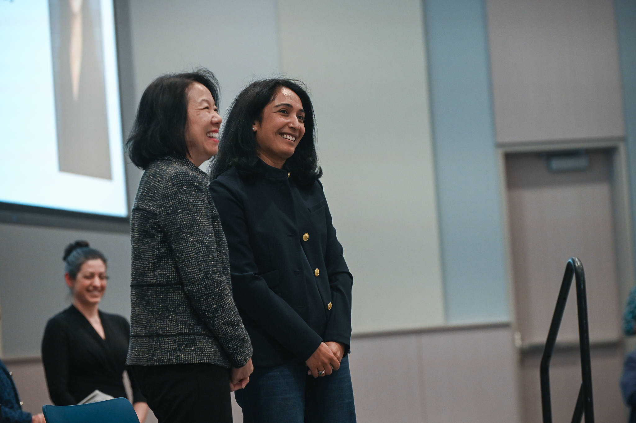 Faculty member smiles for a photo on stage with dean