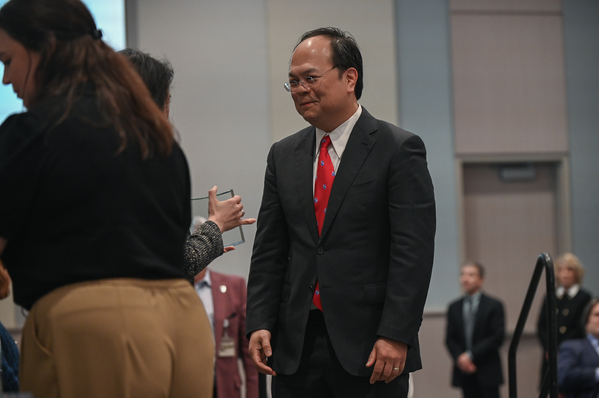 Faculty member receives glass award on stage from dean