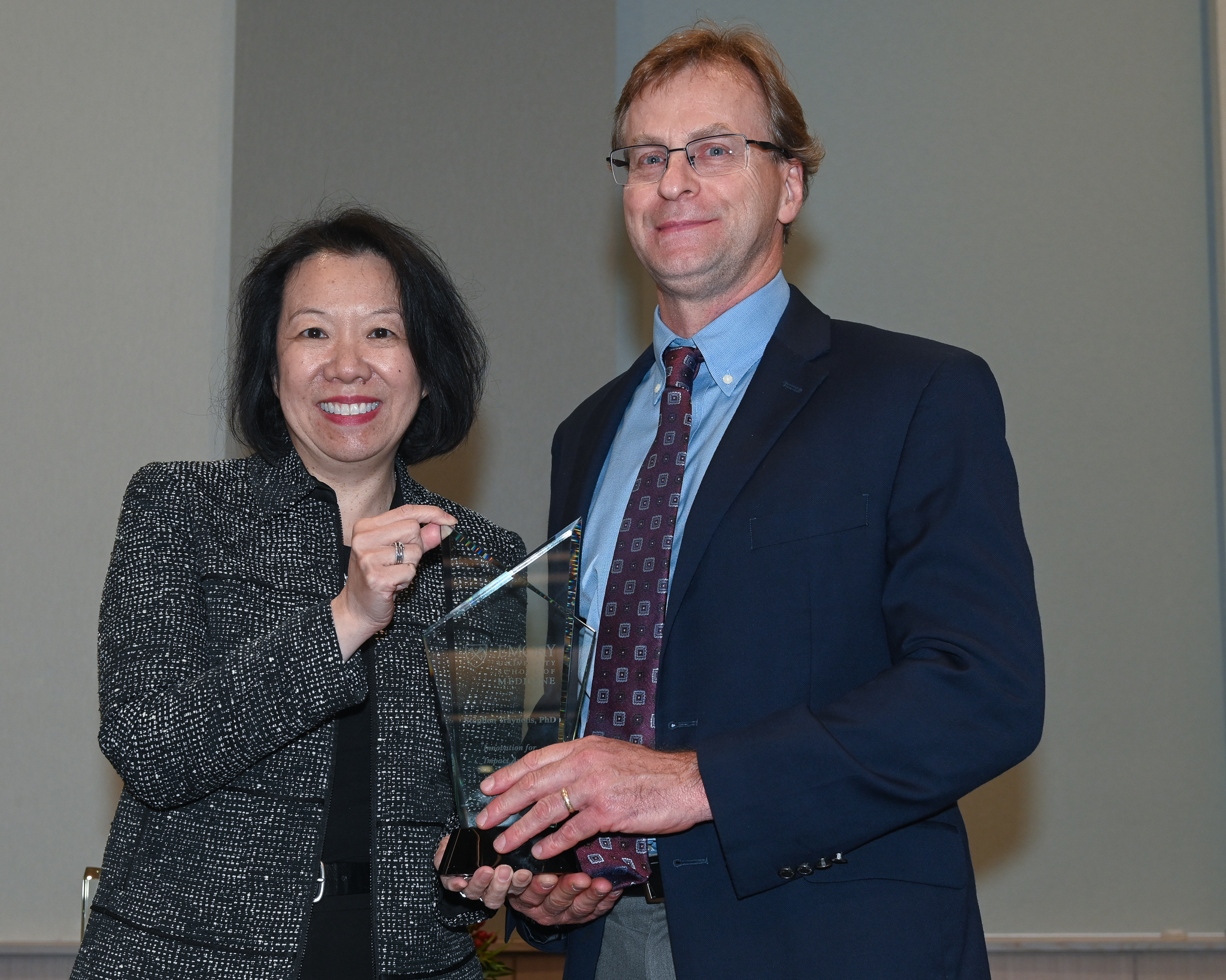 Faculty member accepts glass award on stage with dean