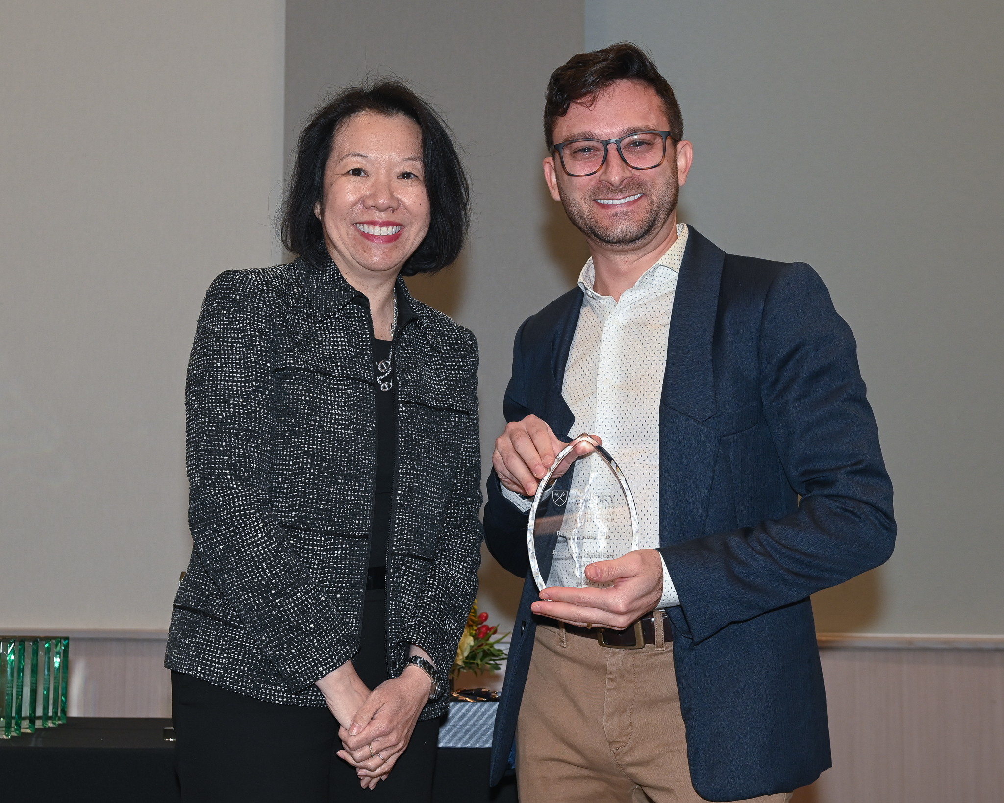 Faculty member accepts glass award on stage with dean