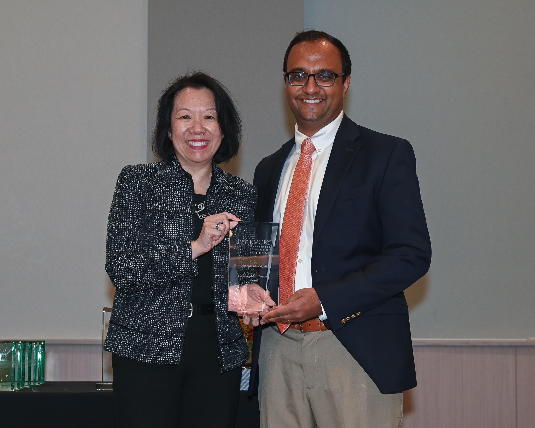 Faculty member accepts glass award on stage with dean