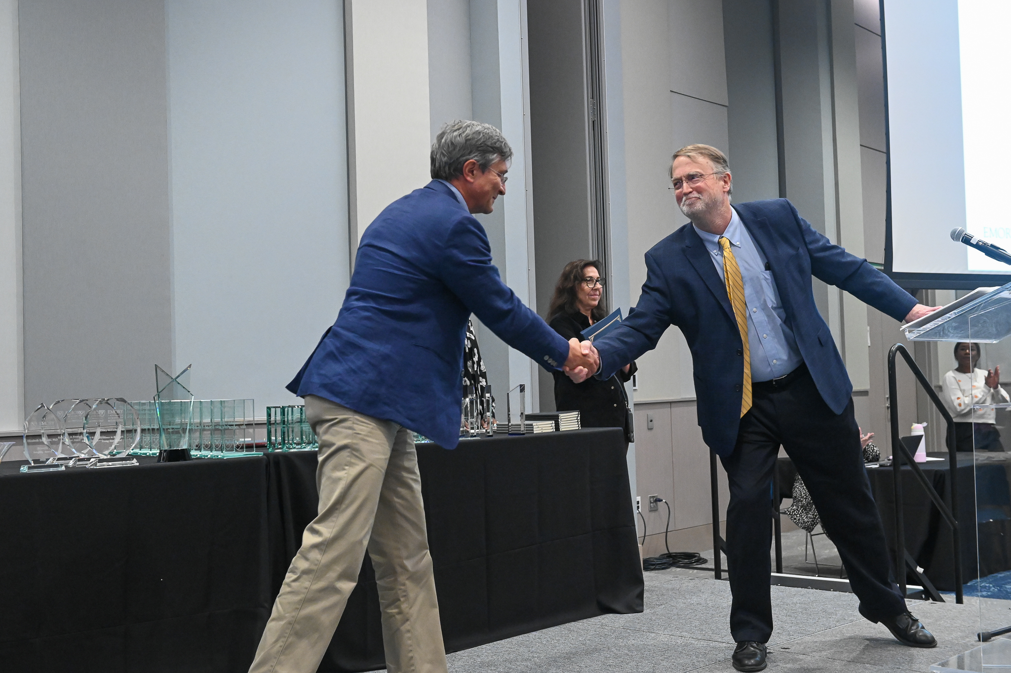 Two men shake hands on stage.