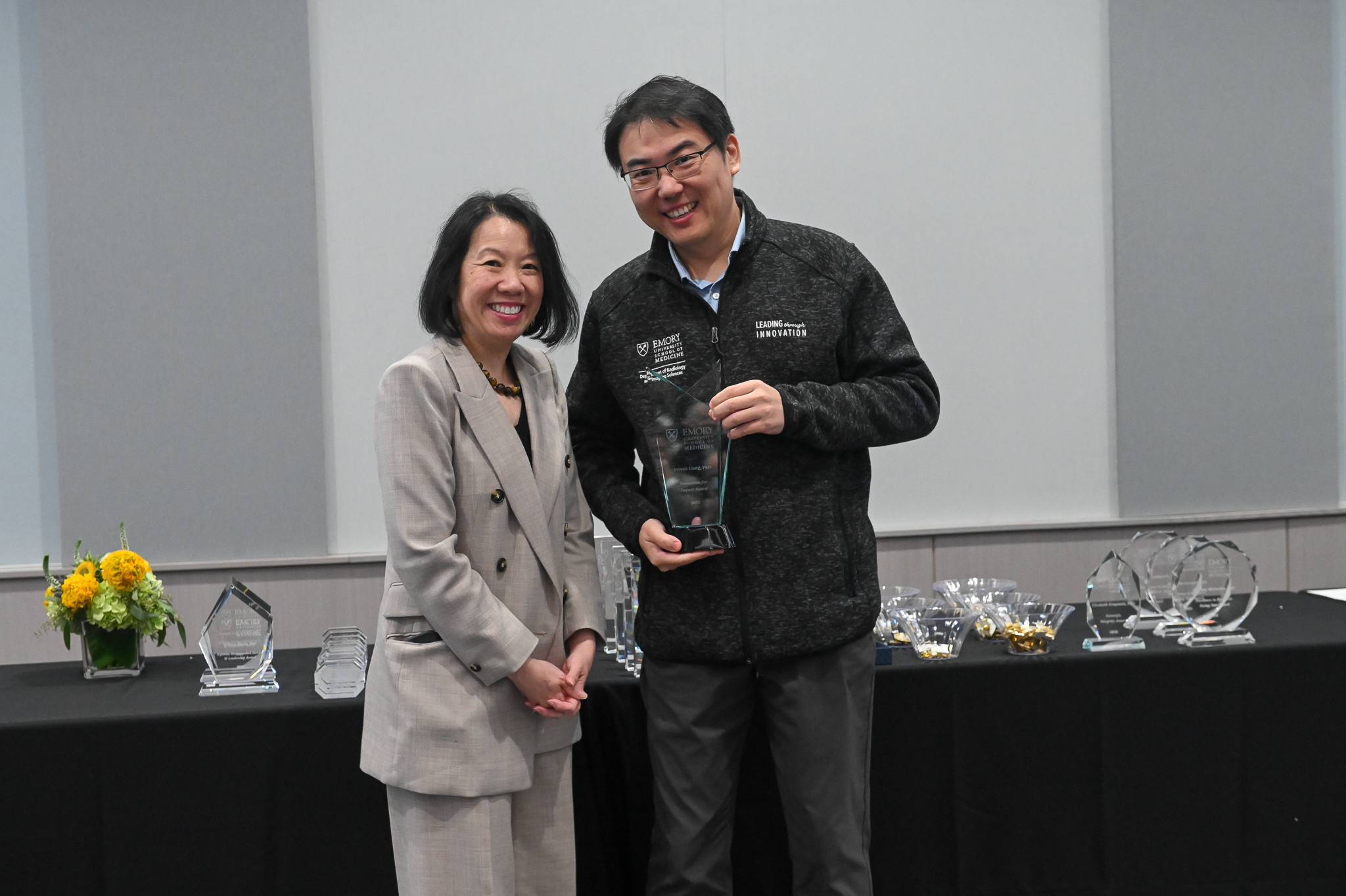 Faculty member accepts glass award on stage with dean