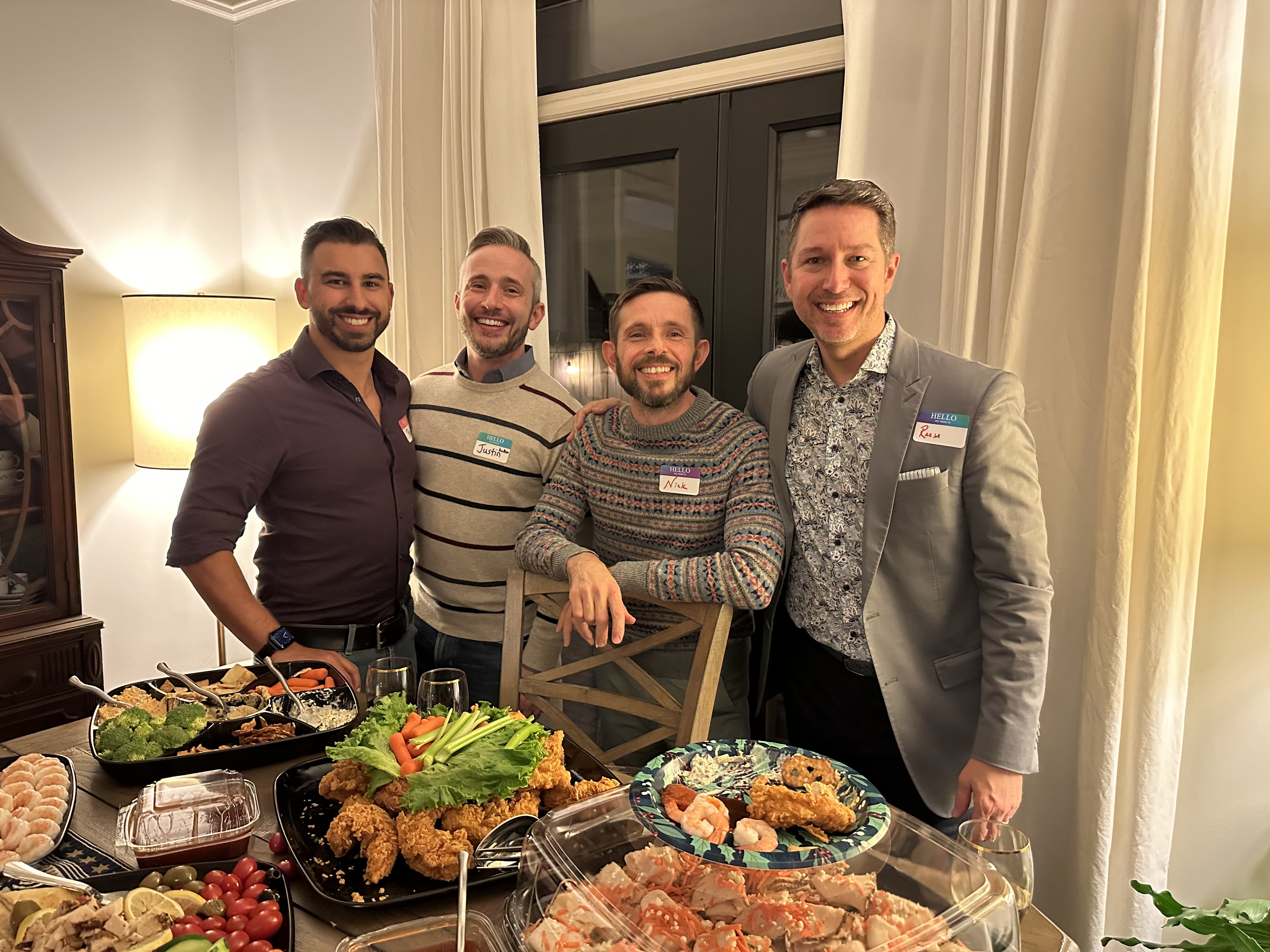 Four men smile for a photo at a dinner party.