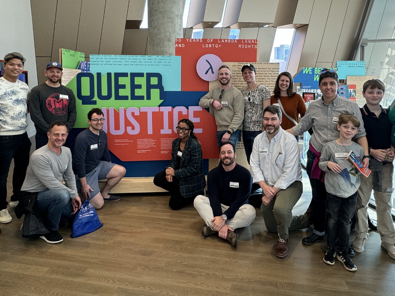 Affinity group stands in front of a Queer Justice museum display