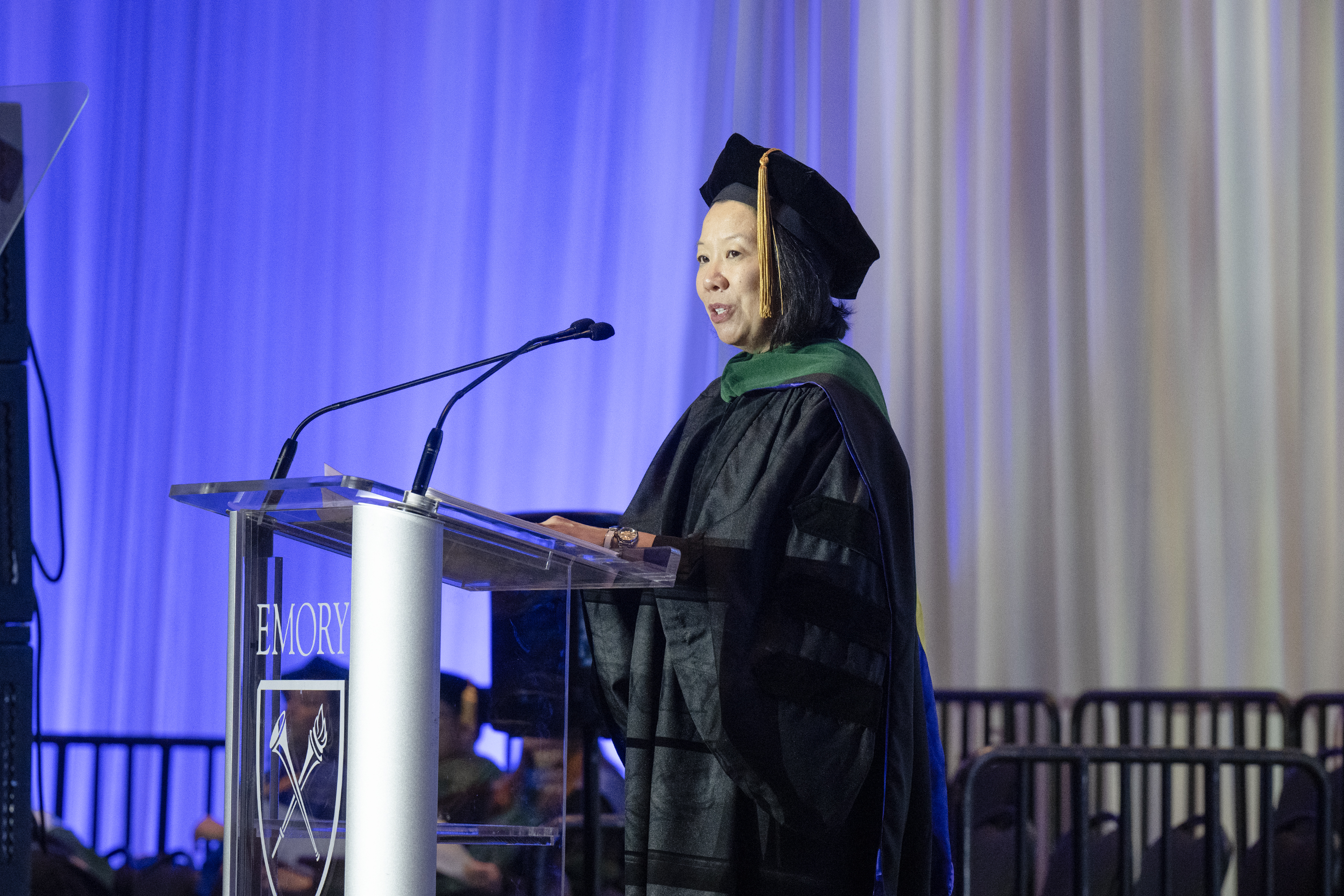 Woman in cap and gown at glass podium