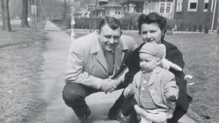 black and white photo of squatting man and woman with a toddler