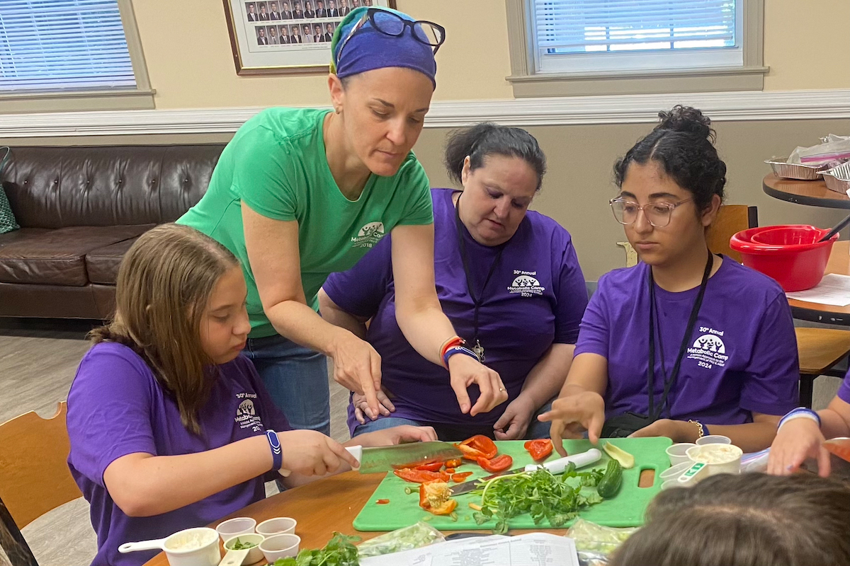 Metabolic dietitian and chef Kristen Narlow (with headband) instructs campers on a special low-protein recipe for pasta salad at the Emory Metabolic Camp.