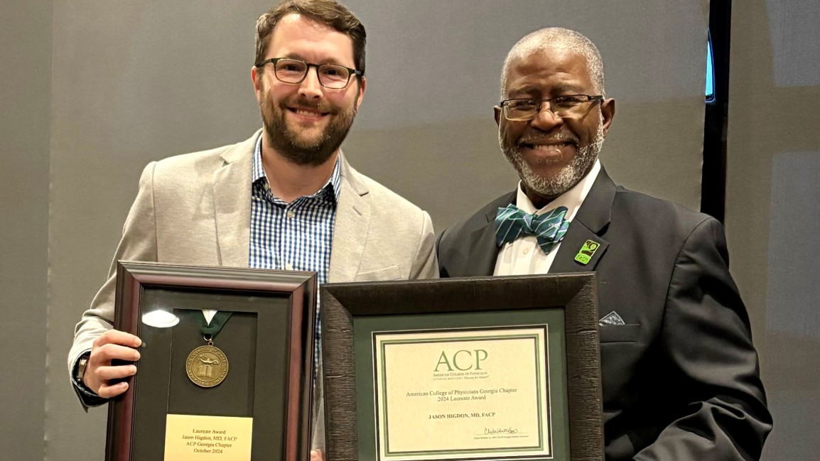 Dr. Jason Higdon holding a framed award and standing next to GA ACP governor Dr. Clyde Watkins, Jr. who is holding a framed certificate