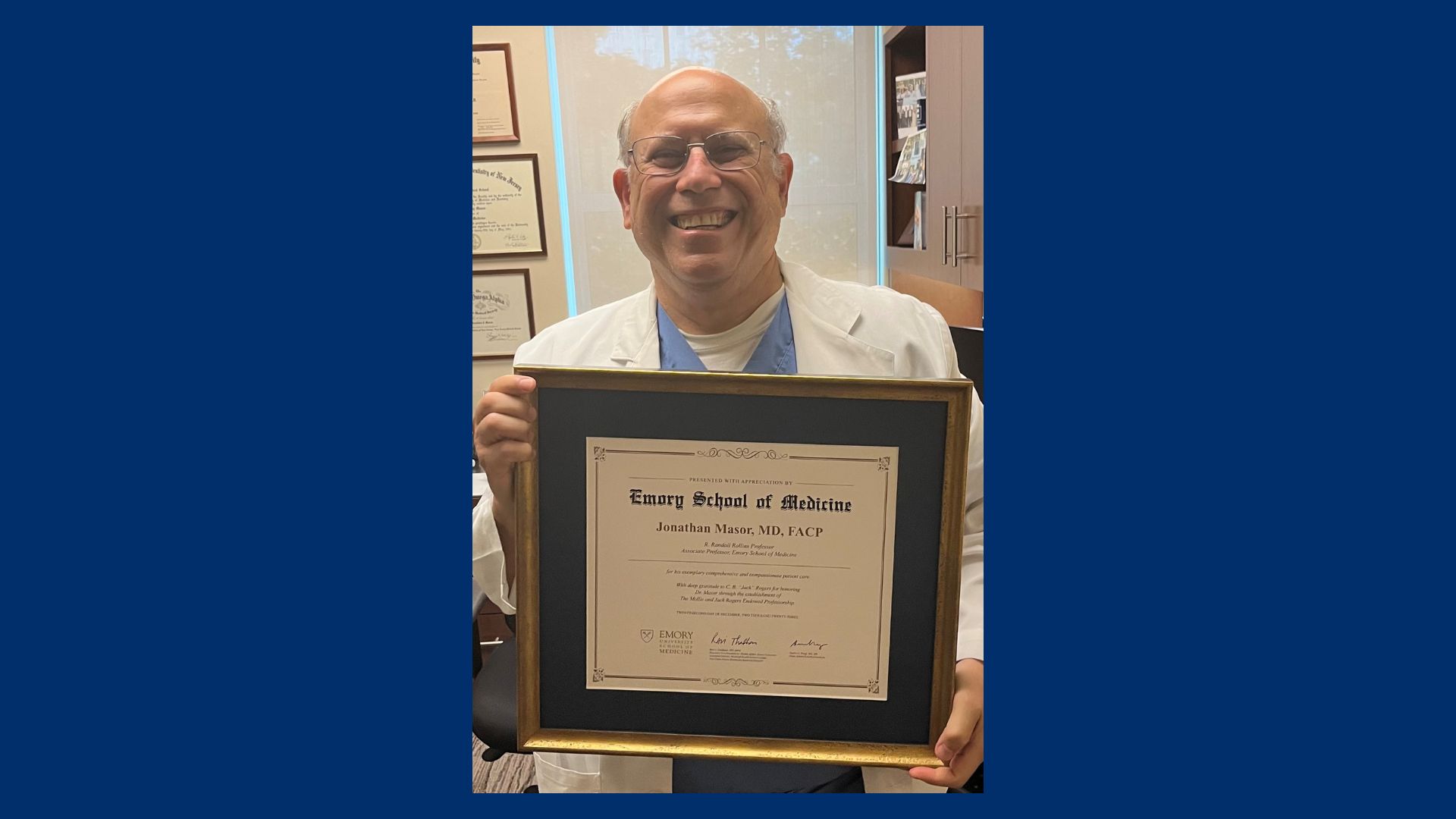 Dr. Jonathan Masor holding a framed certificate naming him Mollie and Jack Rogers Professor