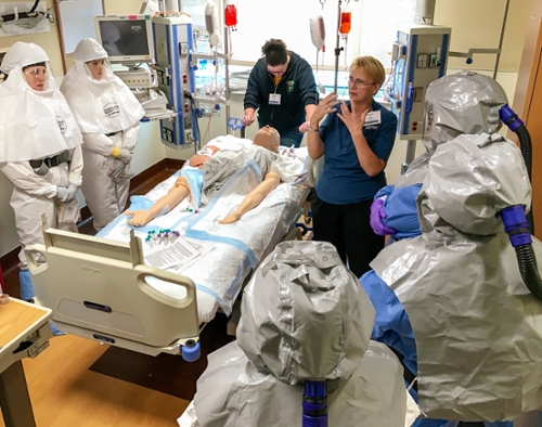 health care workers in protective gear around mannequin