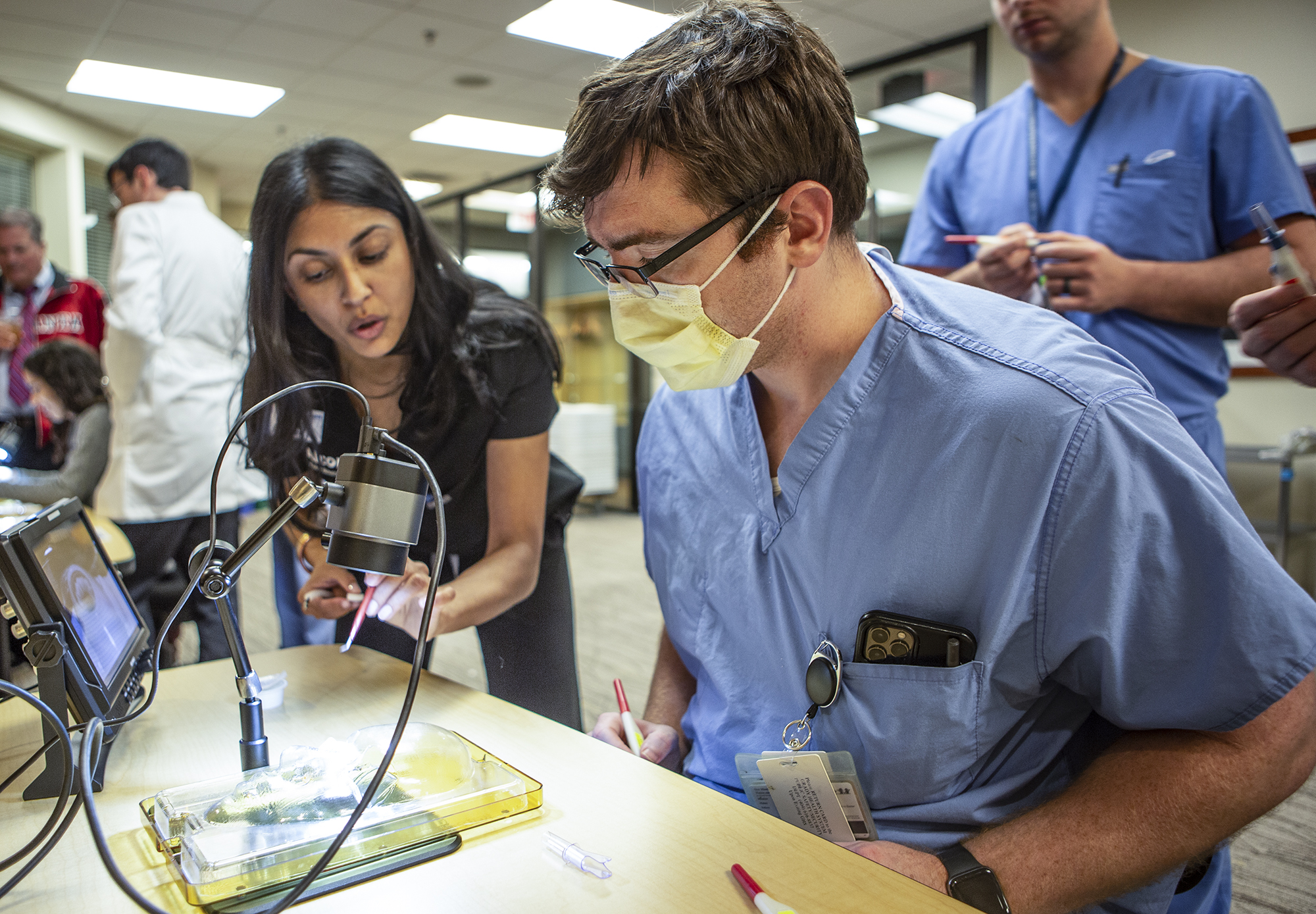 Technician explaining to a third-year resident how to use a proprietary piece of equipment to a third-year resident