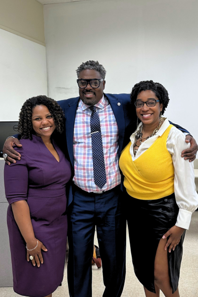 A photo of Dr. Hill and two others embracing at an event or lecture