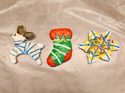 Three decorated holiday cookies on parchment paper.