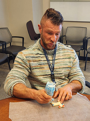 Dr. Alex Orthwein decorating holiday cookies while making a funny face.