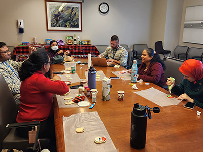 Kesarwala and Orthwein lab teams gather around a table to decorate holiday cookies.