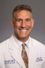 smiling person wearing white doctor coat over a white shirt and colorful tie