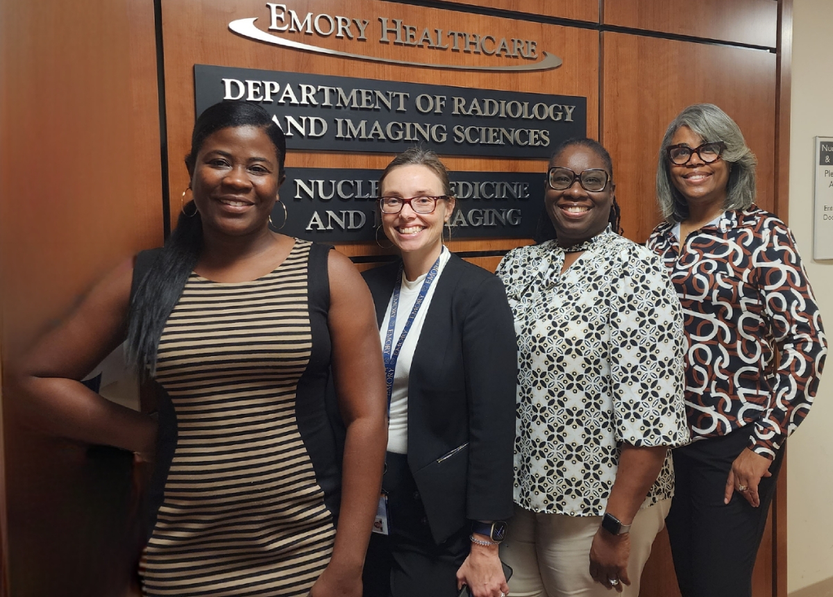 four smiling women in business casual clothes standing in front of sign that says Emory Healthcare Department of Radiology and Imaging Sciences