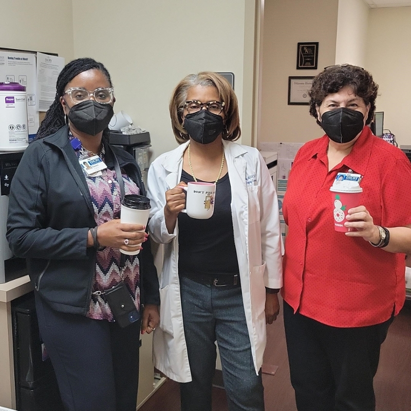 three women wearing face masks and holding coffee cups