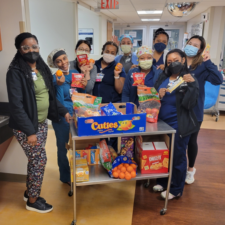 women wearing face masks and hospital scrubs posed around snack cart 