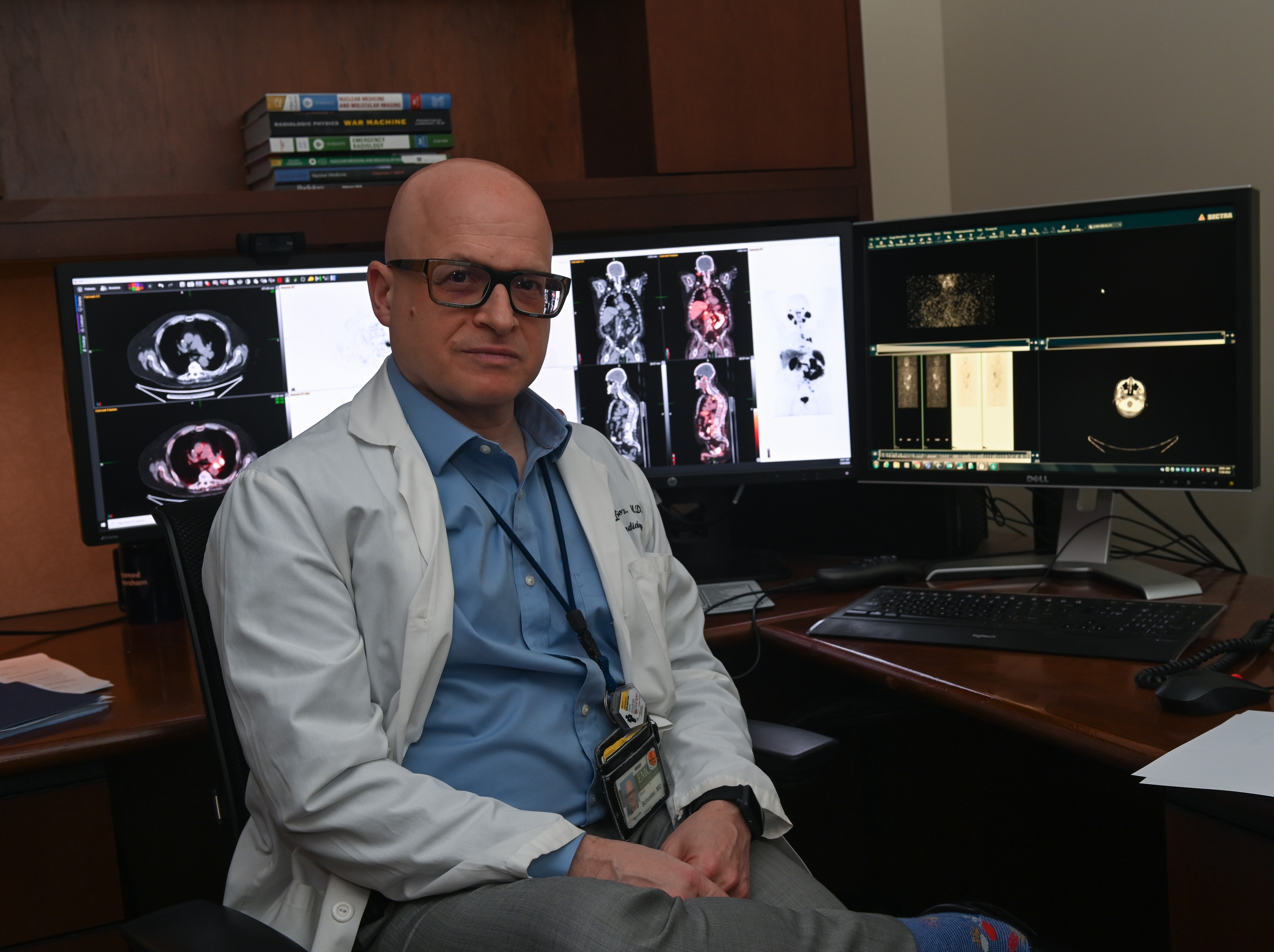 doctor sitting with their back to computer screens with radiology images