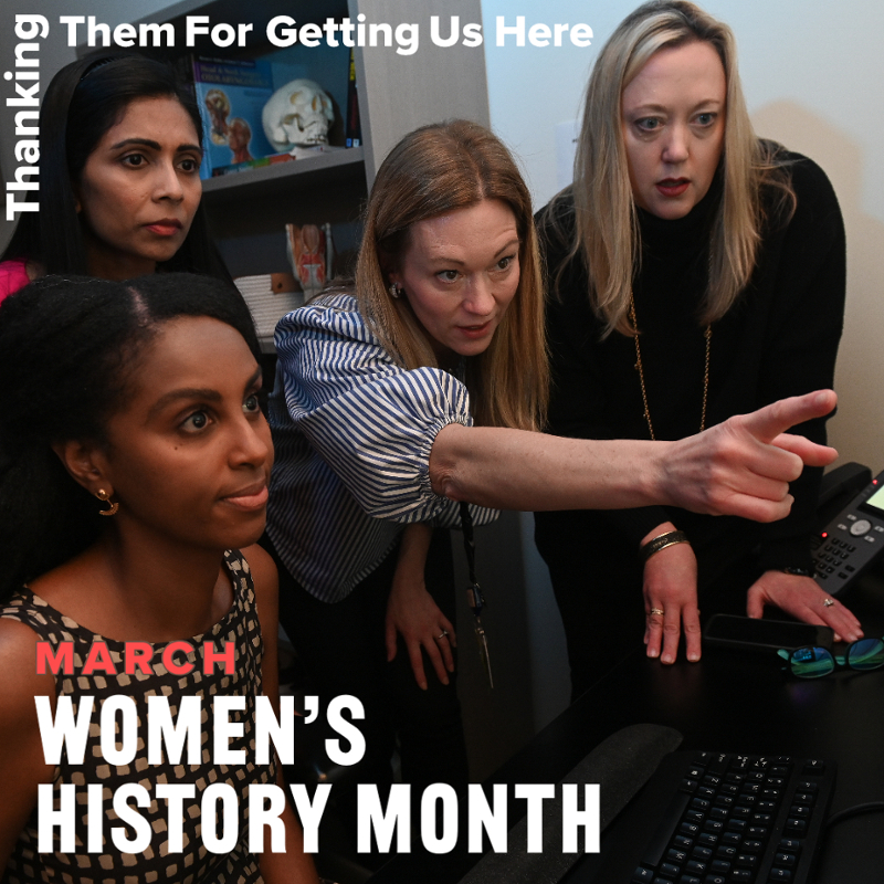 four women looking intently at computer screen while one points to the screen