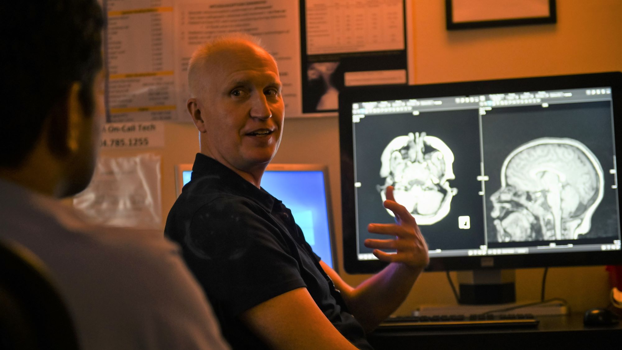 man in darkened room explaining a diagnostic image on the screen behind him
