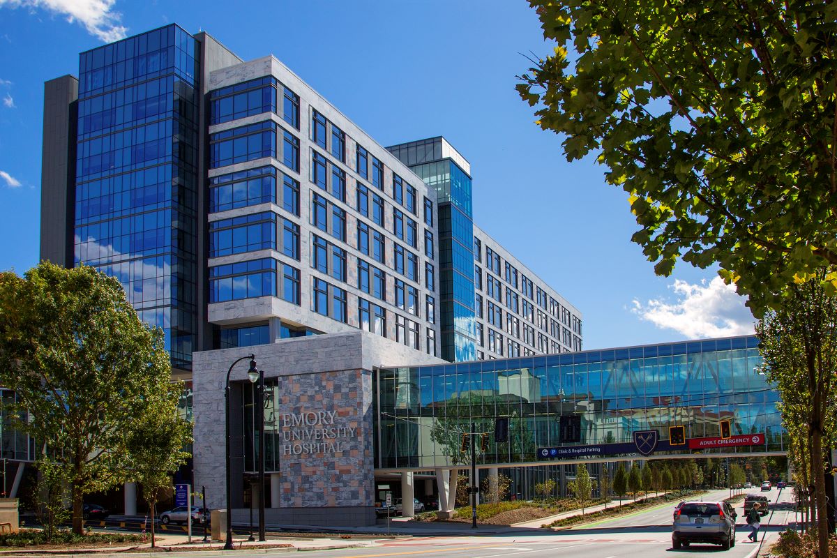 tall hospital building made of glass and marble extending into a blue sky