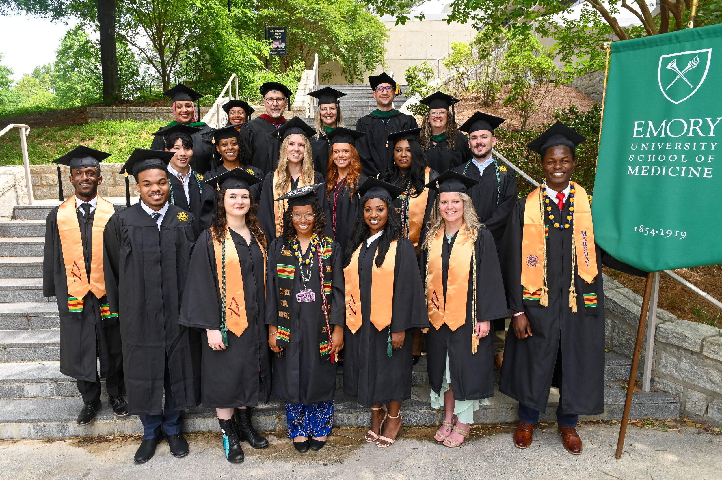 people standing in three rows wearing black graduation caps and gowns