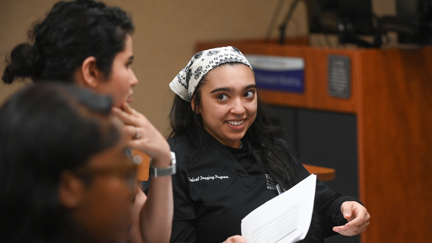 student smiling and holding papers while she speaks