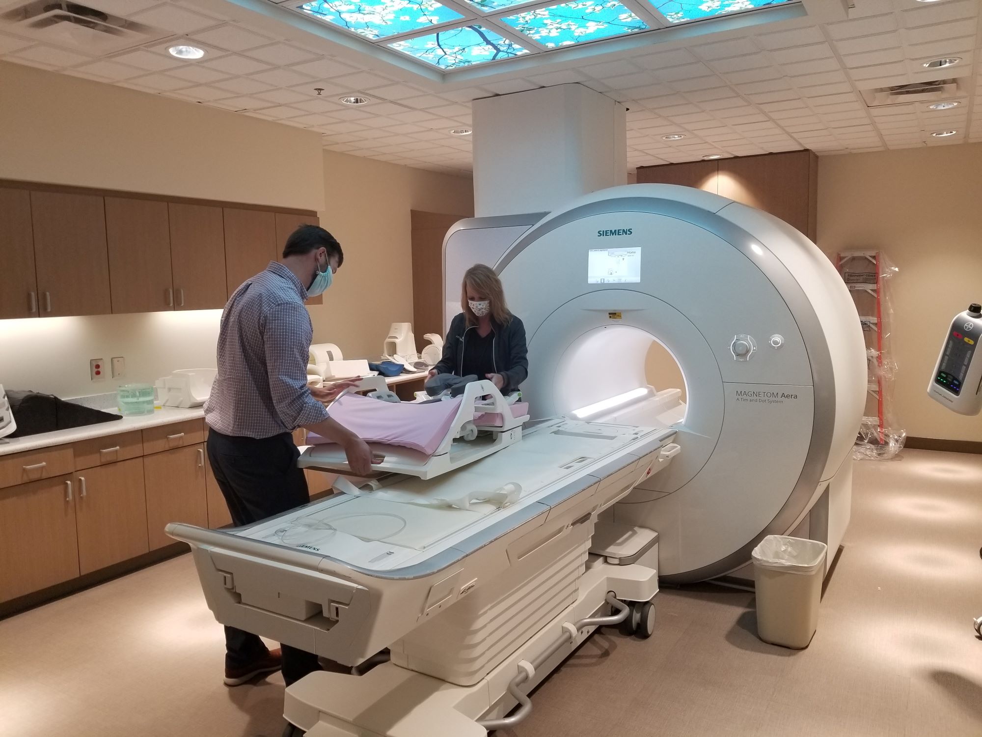 two people positioning the bed of an mri machine