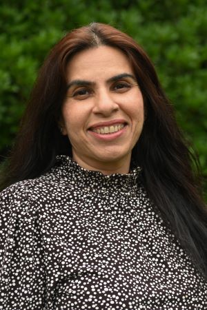 smiling person with greenery in background