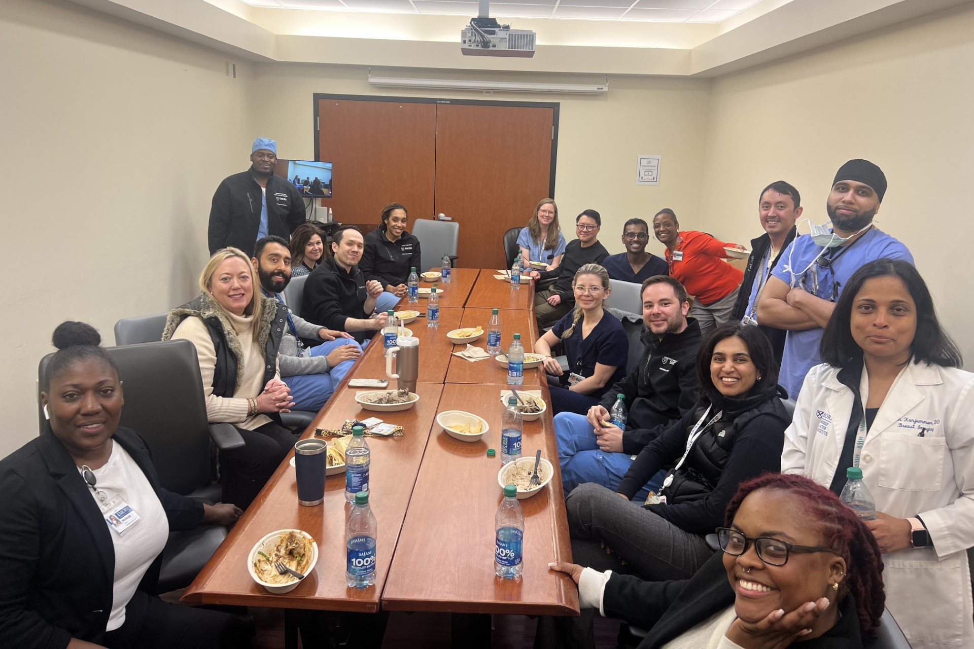 people sitting around a long table smiling w/lunch