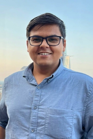 smiling person wearing spectacles and blue oxford shirt