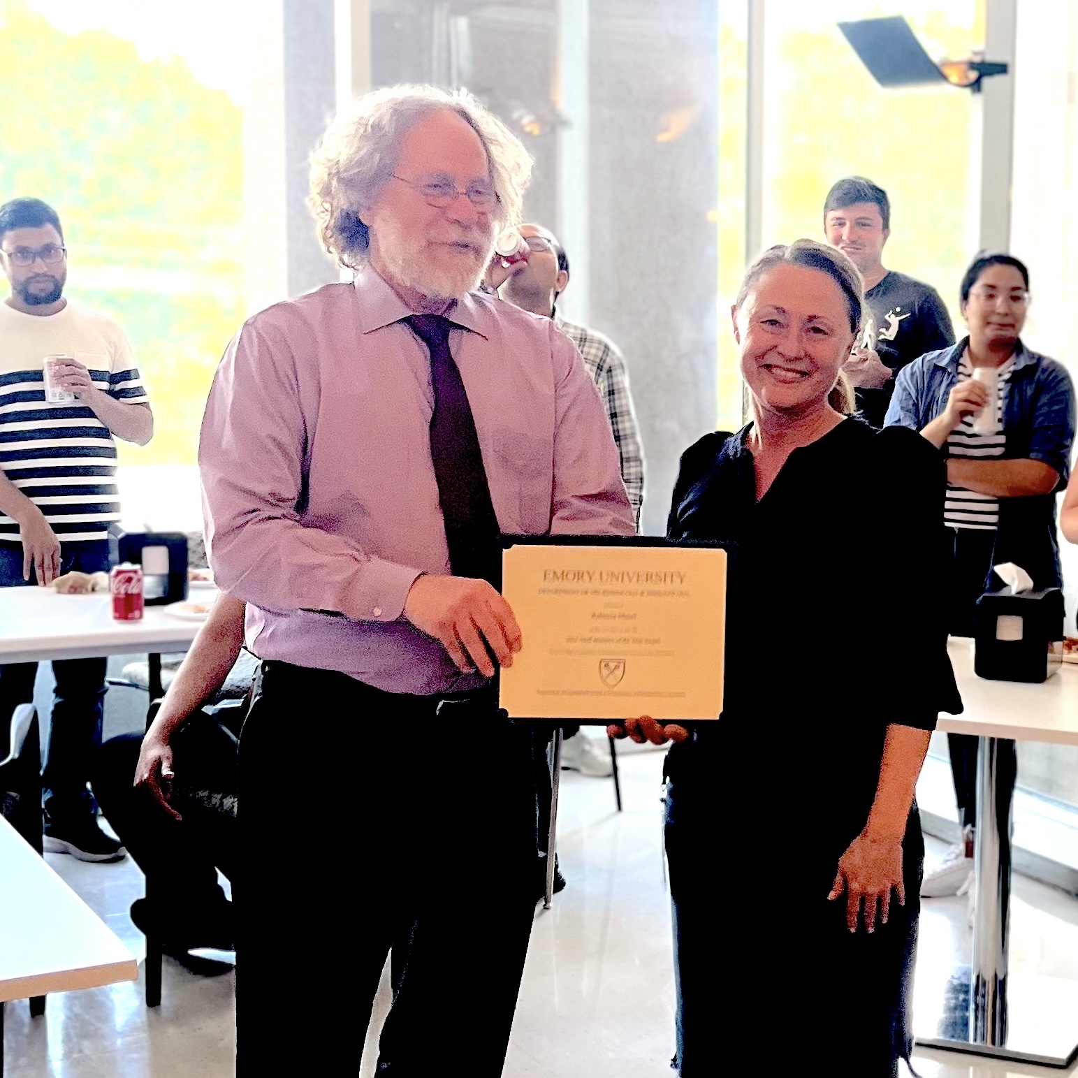 one man, one woman, standing at award ceremony, one person holding a certificate