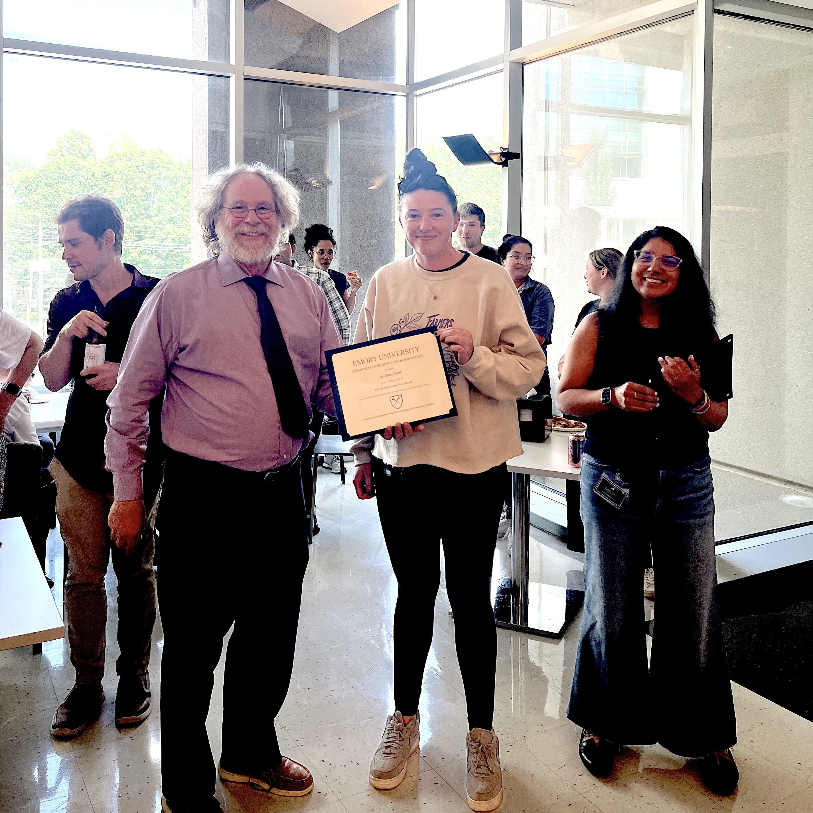 one man, two women, standing at award ceremony, one person holding a certificate