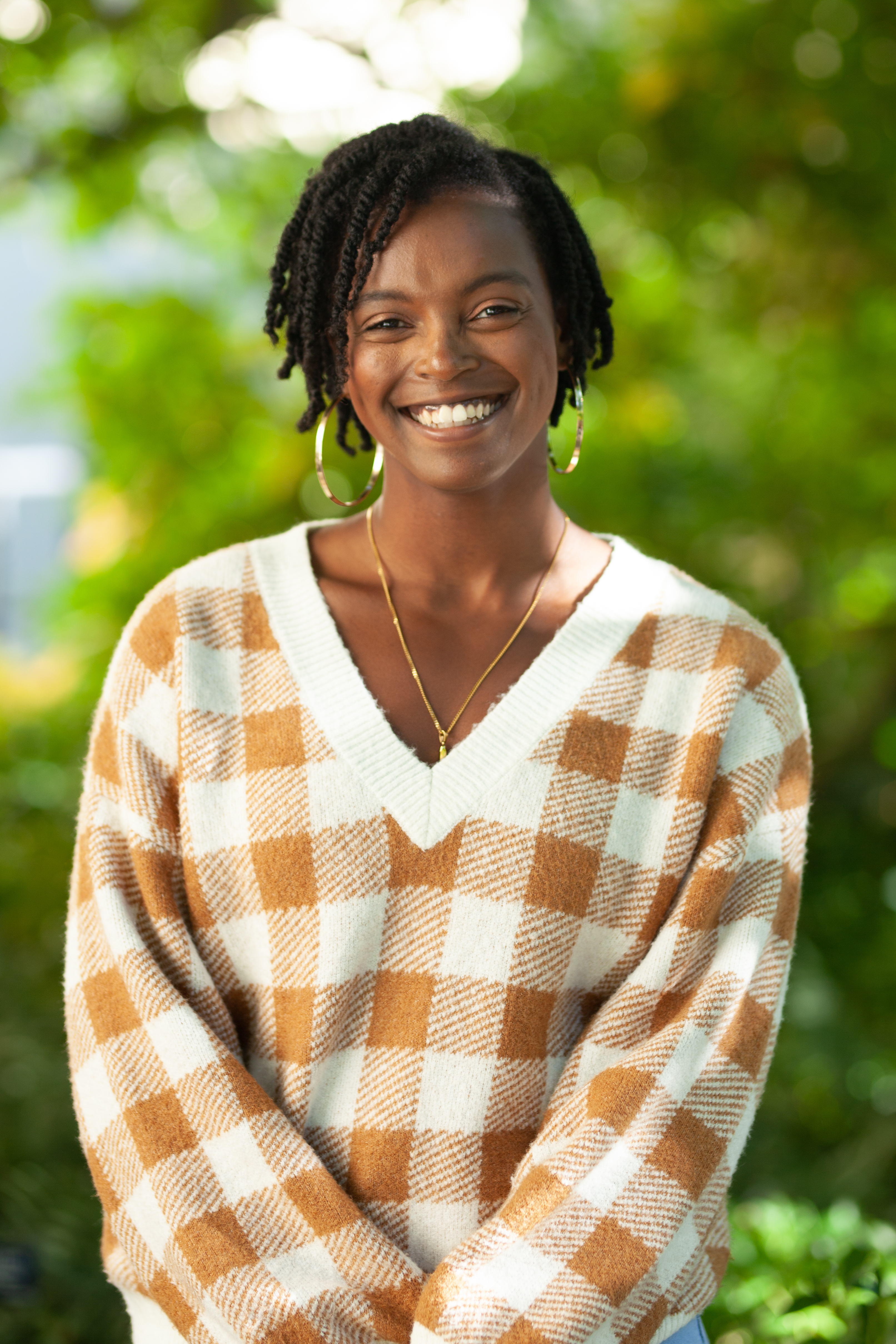 Lauren Askew smiling, wearing a brown plaid sweater