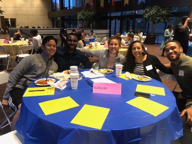 Students sit around a table and smile for the camera at an Emory EMPACT speed mentoring mixer