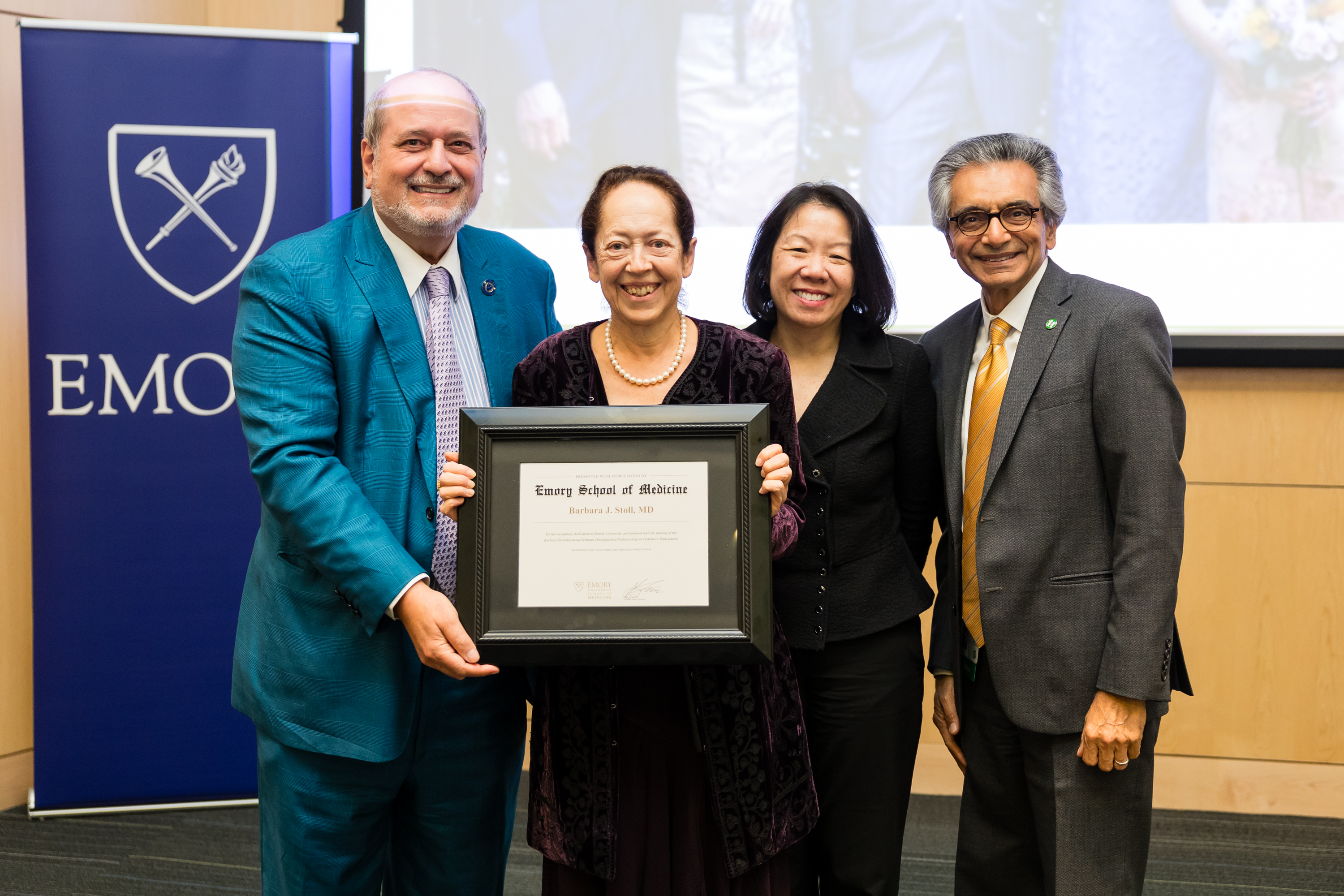 four people smiling for the camera and holding a certifcate