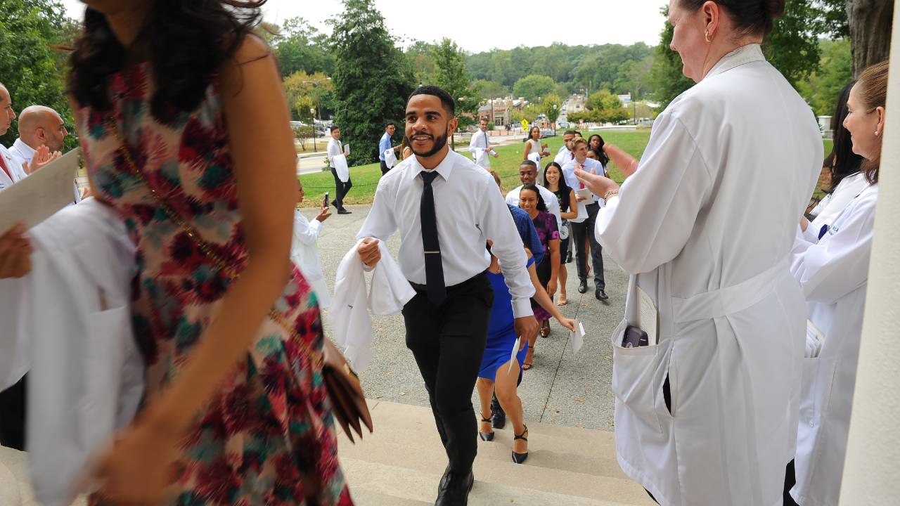 young people walking up stairs holding white coats