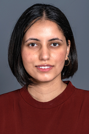 faintly smiling woman with black hair cut in a chin length bob wearing a red top